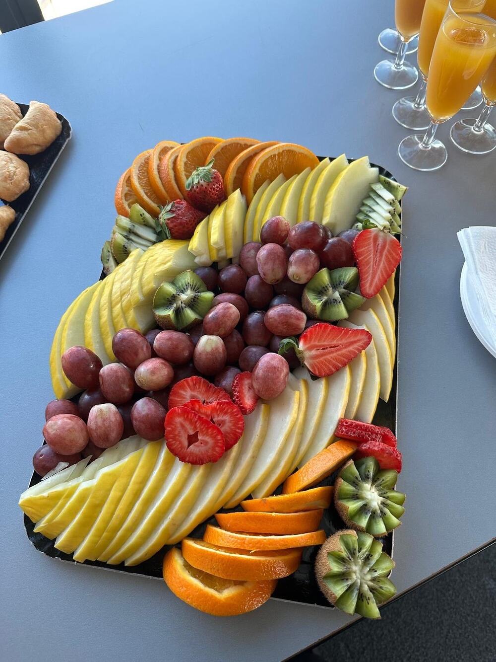 Plateau de fruits frais tranchés et mimosas, dressés pour un brunch d'entreprise